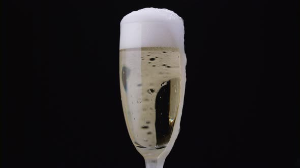 Glass of Champagne with a Rotating Bubbles Inside. Black Background. Close Up
