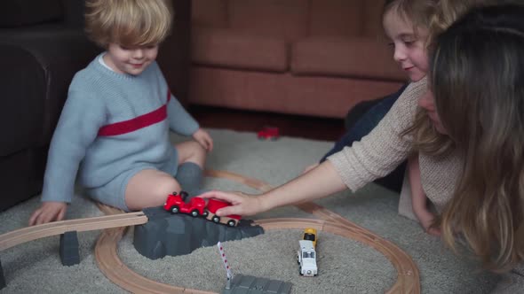 Mother with kids playing with toy roadway