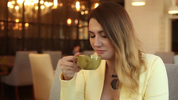 Business Girl Drinking Tea Sitting at a Table in a Cafe