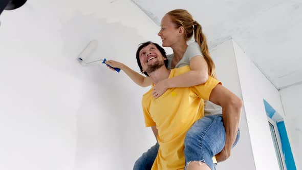 A Happy Man and Woman Paint the Wall Using a Roller Painter