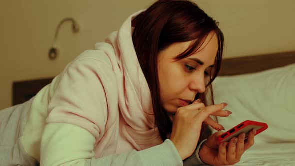 Young Woman Lying on Bed with Mobile Phone