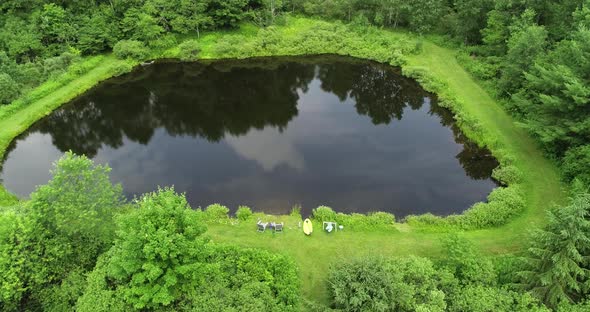 Clouds and trees reflect in a small private fishing pond in the catskill mountains of New York.