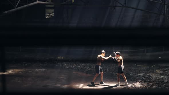 4K Asian man boxer do practicing boxing with male coach in abandoned building.