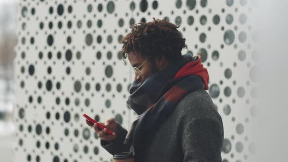 Cheerful Black Man Using Smartphone and Posing Outdoors