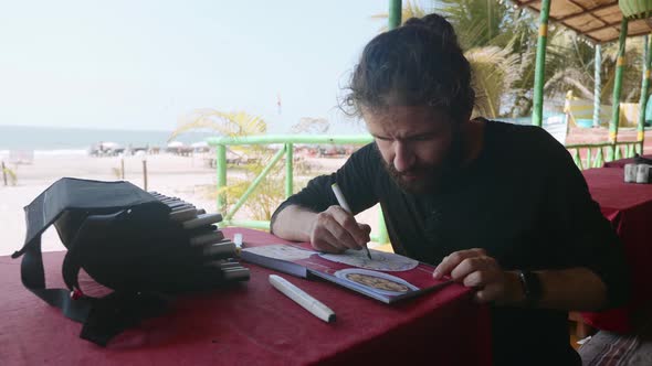 Man Sits in Cafe and Drawing Image of Indian Food in Sketchbook By Art Markers