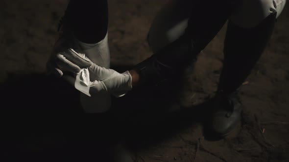 Female Vet Bandaging A Seal Brown Injured Horse Standing On The Sandy Ground