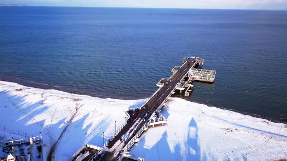 Gdansk Brzezno pier in winter, aerial shot. Flying sideways, looking at the pier and water. Sunny wi