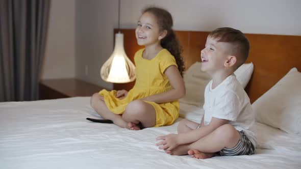 Happy Cute Little Kids While Watching TV on Laptop. Boy and Girl Watch Cartoon on Laptop on Living