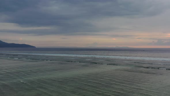 aerial of small waves ripple continuously during low tide through the ocean at sunset