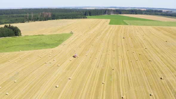 Aerial Drone Shot  a Field with a Tractor and Hay Bales in a Rural Area on a Sunny Day
