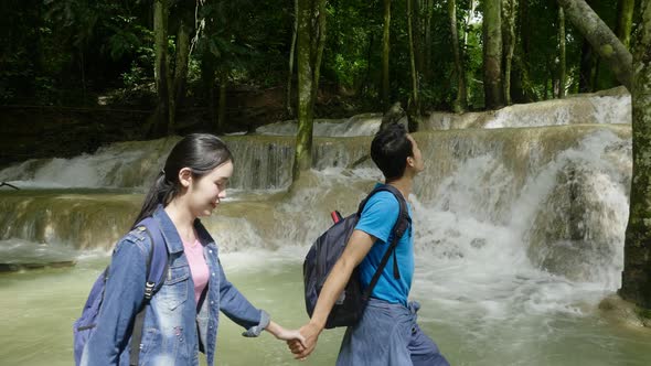 Couple Holding Hand And Walking In Waterfall