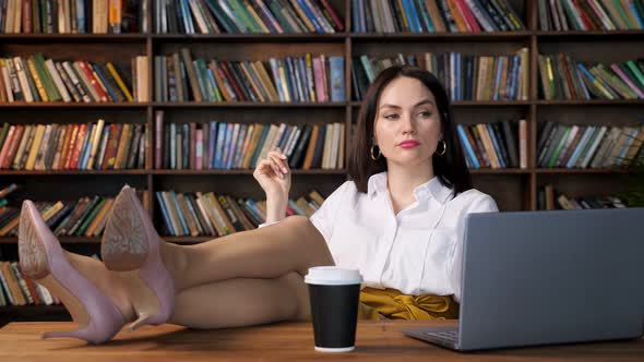 Short Haired Brunette with Red Lipstick Looks at Grey Laptop