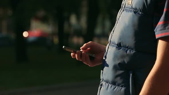 Male Scrolling and Scaling Screen on Smartphone at City Park