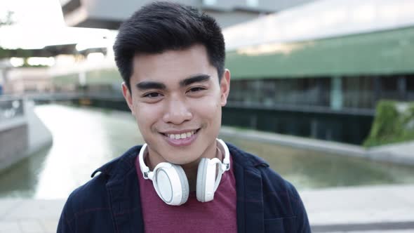 Portrait of Handsome Young Asian Man with Headphones Looking at Camera