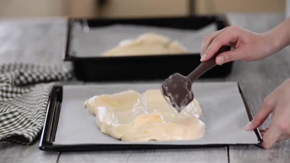 Female Hand with Silicone Spatula Spreads Batter on Baking Tray