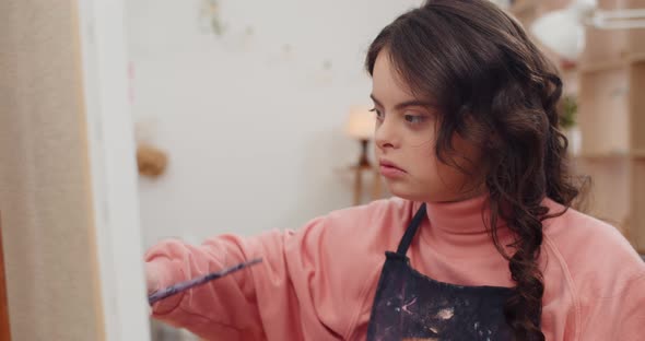 Close Up View of Pretty Teen Wearing Aprone with Genetic Disorder Painting in Her Room, Concentrated