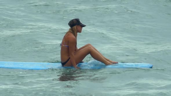 A young woman surfing in a bikini on a longboard surfboard.