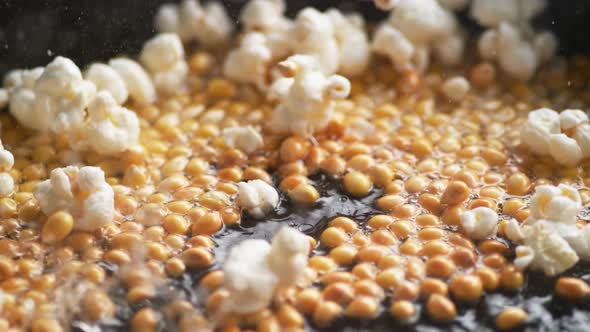 Popcorn popping on heated fry pan. Slow Motion.