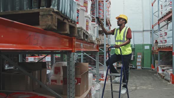 Male Worker in Hard Hat Scanning Boxes in Warehouse