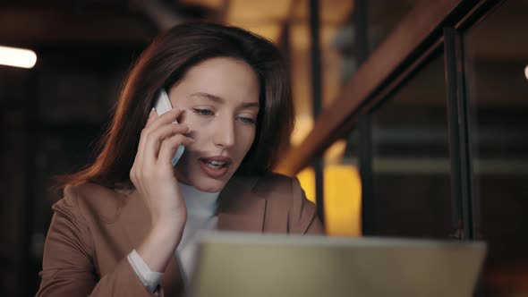 Woman Having Mobile Call While Sitting at Cafe with Laptop