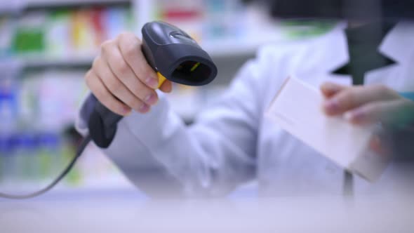 Unrecognizable Pharmacist Cashier Scanning Pills Box with Device Stretching Medication in Slow