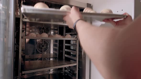 Baker Puts Baking Sheet of Raw Croissants Into the Combi Oven