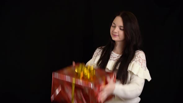 Young Woman with a Gift Box on Black Background, Gift Box with White Ribbon for Happy New Year