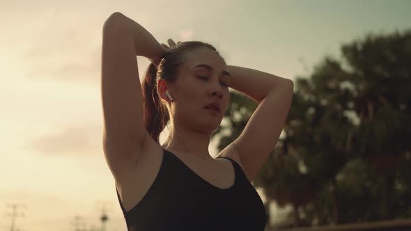 Woman wearing wireless headphones and  tie hair making ponytail ready to exercise in sportswear.