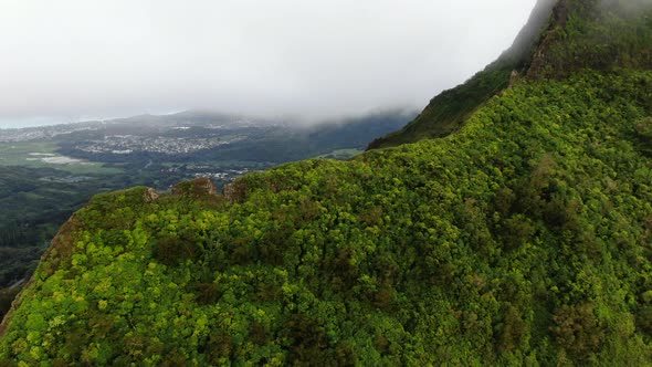 Drone flying over hawaiian mountain overlooking east oahu town on a rainy day