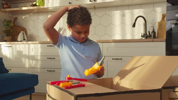 Positive School Age African Boy Repairing Diy Cardboard Car with Toy Tools