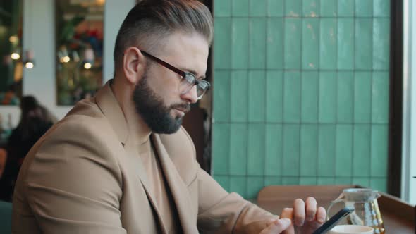 Businessman Using Smartphone in Cafe