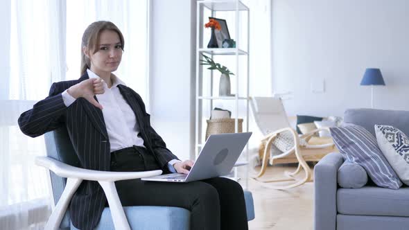 Thumbs Down by Young Woman at Work,  Looking at Camera