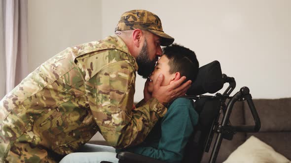 Military Soldier Father Kissing Kid Son with Disability on Wheelchair During Home Return Family Love