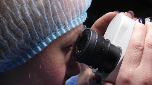 Female Researcher Looking Through Microscope