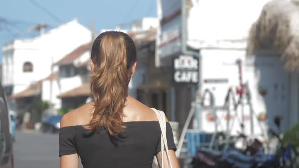 Lady Walks Along Street Approaching Cafe Under Sunshine