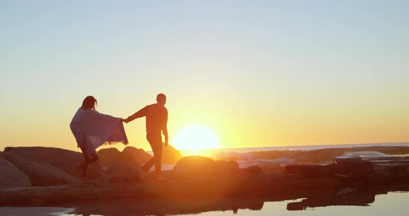 Couple walking with hand in hand on rocky shore 4k