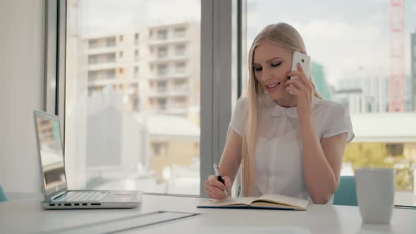 Serious Woman Working in Light Office Room. Elegant Modern Business Woman with Laptop and Papers at