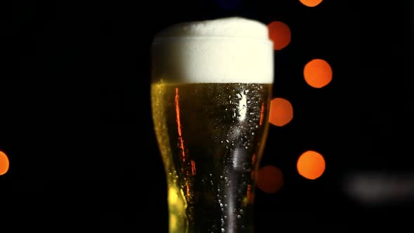 A Glass of Cold Beer on a Black Background with Colored Lights