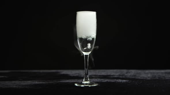 Dry Ice Bubbling in a Glass of Champagne at Black Background