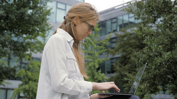 Young business woman using portable computer in green park