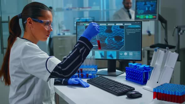 Woman Technologist Doing a Laboratory Test Examining a Flask with Blood Sample