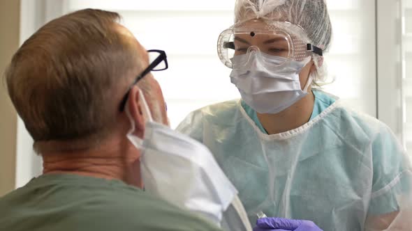 Hospital Worker in a Protective Suit Takes a Swab From an Elderly Patient for Coronavirus