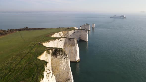 Aerial forward along coastal edge of Old Harry Rocks cliffs and boat in background, county Dorset in