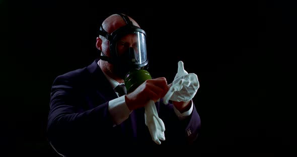 Portrait of a Man in a Business Suit and a Gas Mask on a Black Background. He Is Holding and Wearing