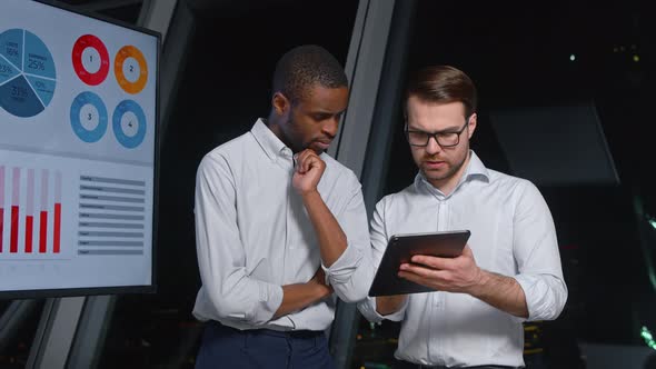 Two young colleagues at meeting to discuss the company's strategy using digital tablet