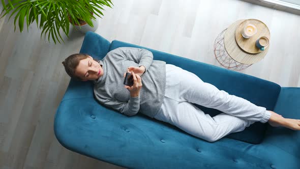 Overhead Shot of Happy Relaxed Woman Holding Smart Phone Using Mobile Apps Watching Funny Video