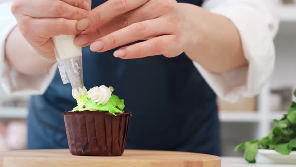 Woman Confectioner Hands Applying Whipped Sweet Cream on Cupcake