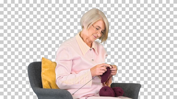 Elderly woman in glasses knits clothes, Alpha Channel