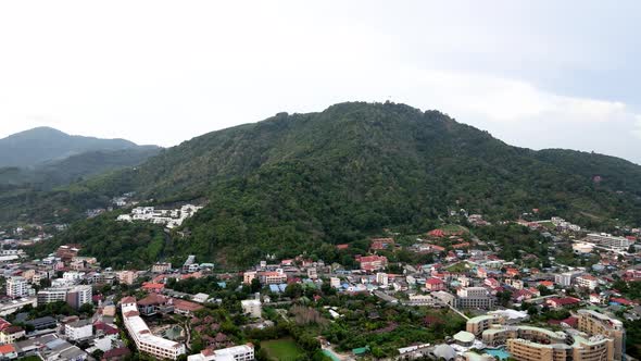 Aerial Flying Towards Forested Hillside Over Buildings In Phuket. Dolly Forward, Establishing Shot