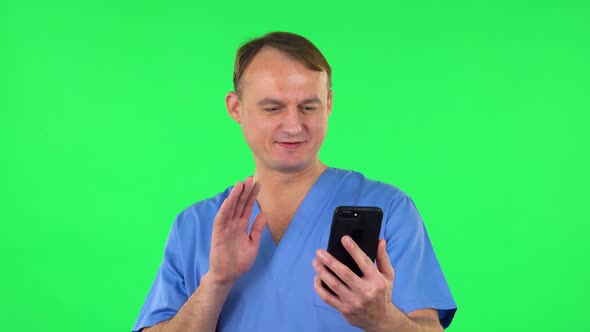 Smiling Man Talking for Video Chat Using Mobile Phone and Rejoice on Green Screen.